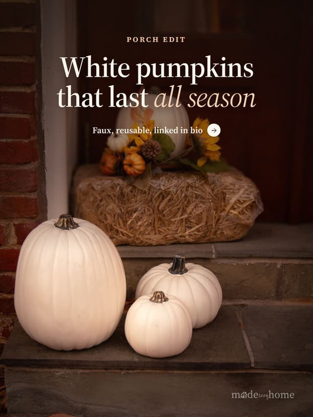 White pumpkins on porch steps beside a hay bale and fall florals
