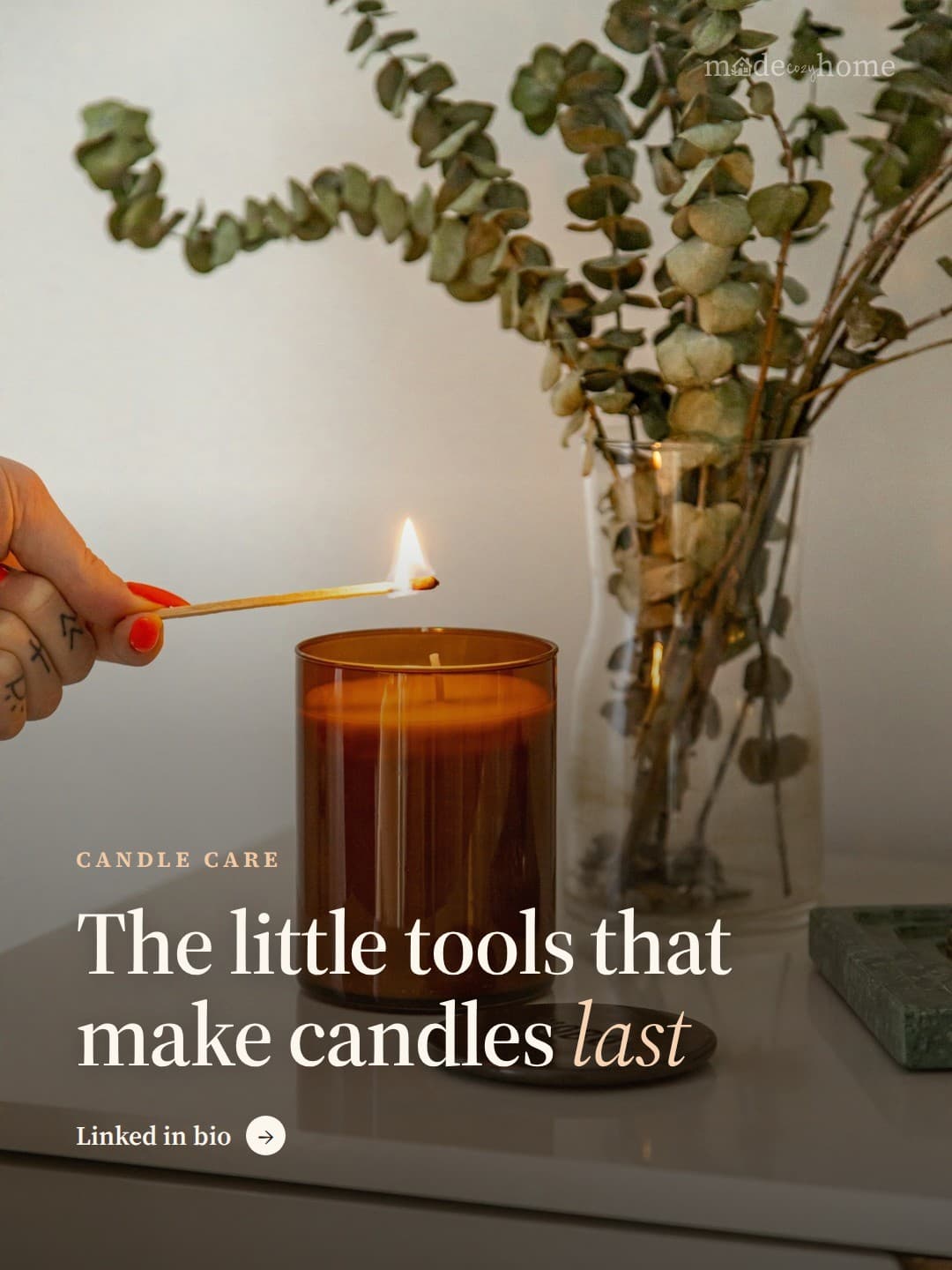 A hand lighting a candle in a brown glas