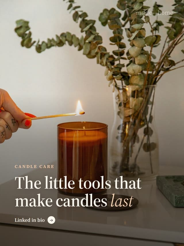 A hand lighting a candle in a brown glas